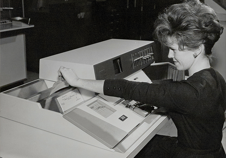 Women feeding cheques into printer